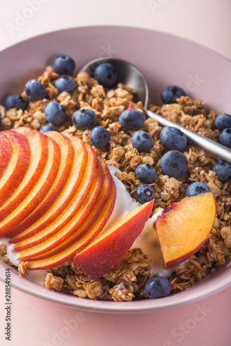 Bowl of granola with yogurt, peach slices and bluberry