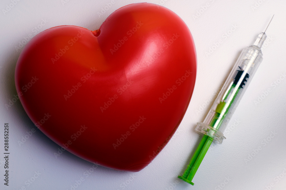 Syringe and a red blood stain in heart shape Syringe and a red blood stain in heart shape