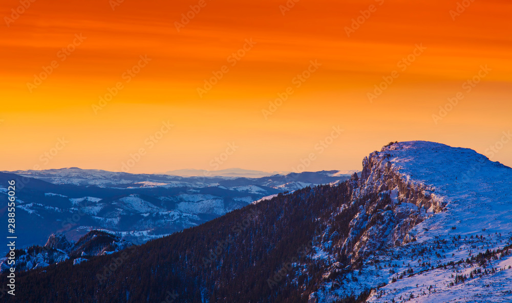 golden sunset in winter mountain landscape. Ceahlau, Romania