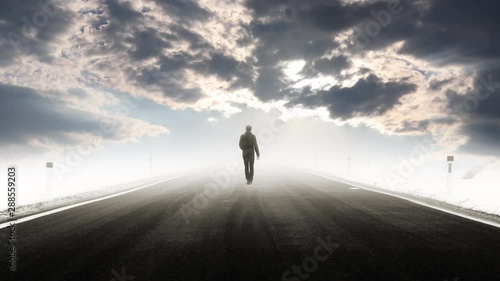 Man walks alone  on foggy mysterious asphalt road with cloudy sky time lapse. Conceptual straight freeway roadway. photo