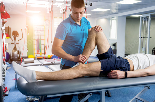 Rehabilitation therapy. Physiotherapist working with young male patient in the rehabilitation center photo