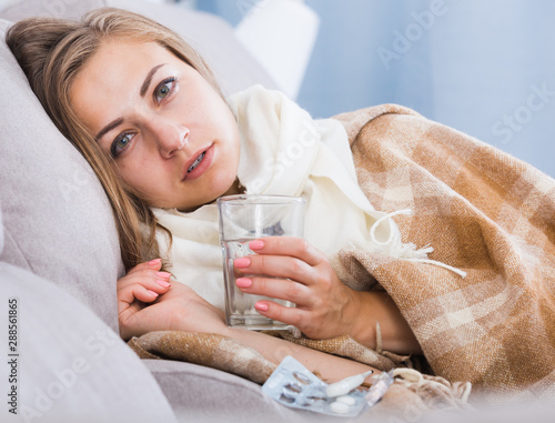 Canvas Print Ill girl on couch with drink and medicine