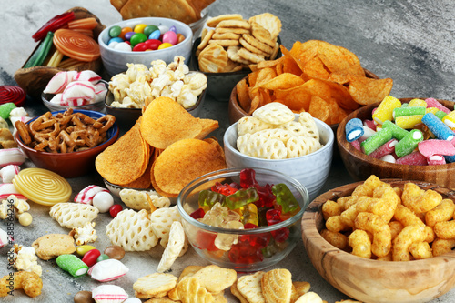 Salty snacks. Pretzels, chips, crackers and candy sweets on table
