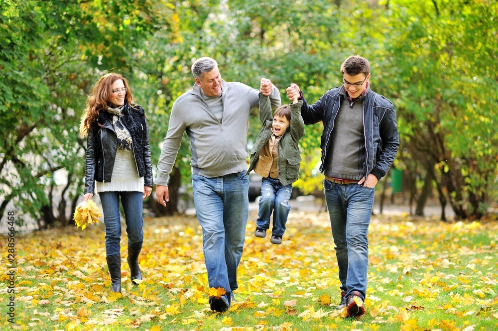 Obraz premium Happy family walking together in autumn park