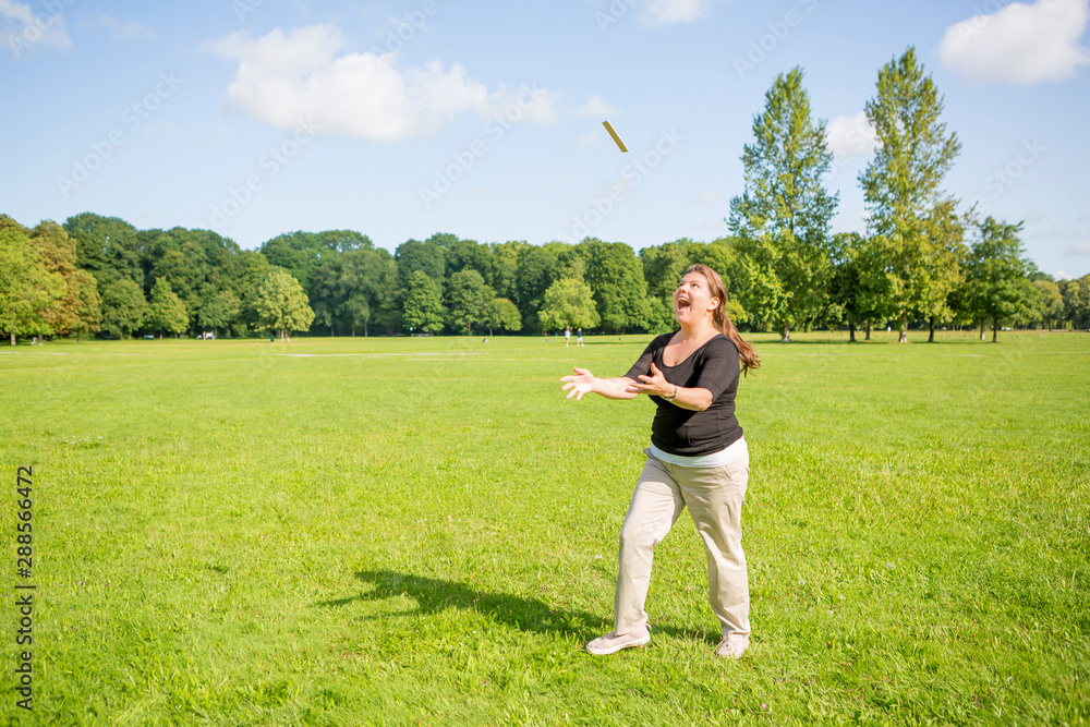Woman in a park cheerfully tosses her phone up as a reaction for celebration of good news.