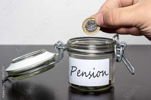 Dropping one pound coin into jar for Pension photo