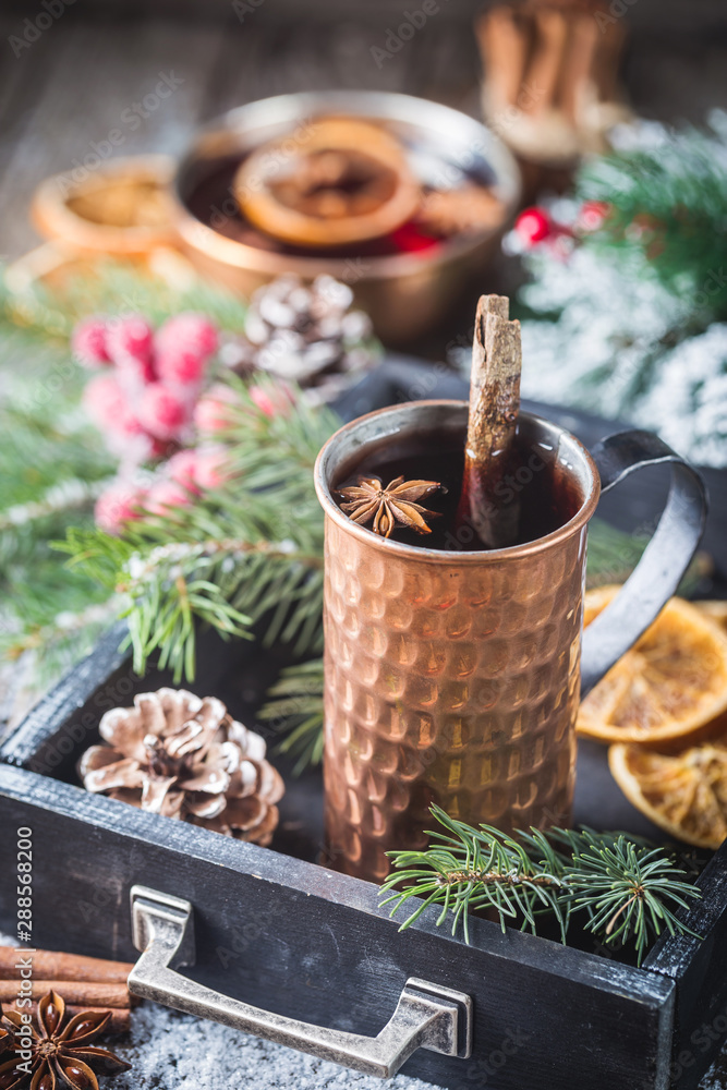 Christmas mulled red wine with spices and fruits on a wooden rustic table. Traditional hot drink at Christmas time