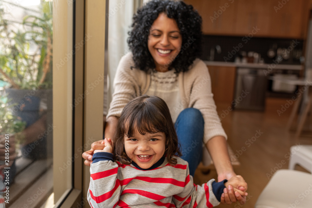 Fototapeta premium Smiling little girl and her mother sitting together at home