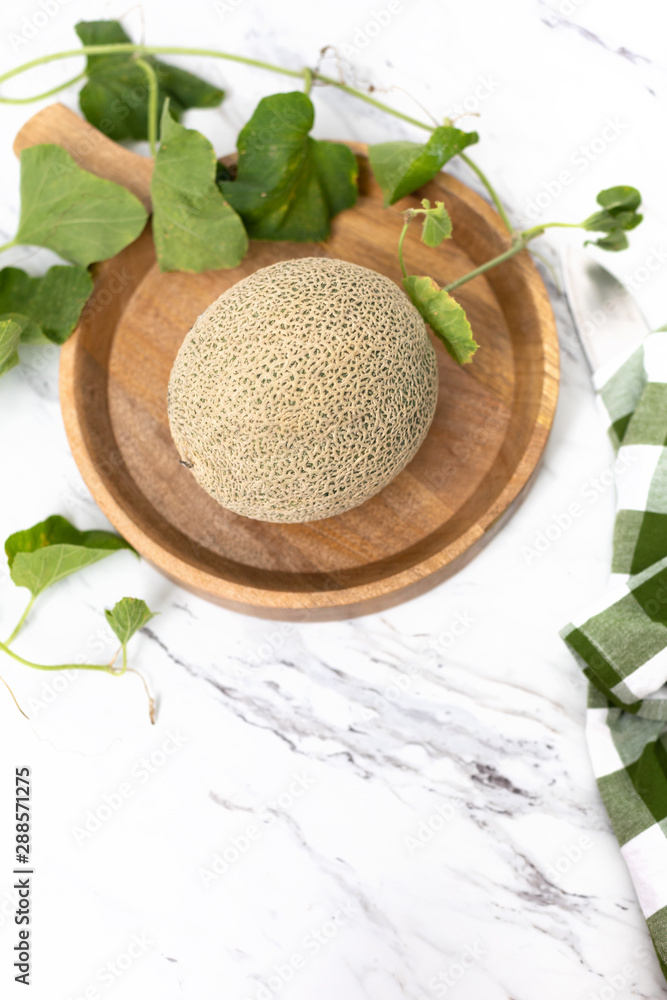 Whole Freshly Picked Cantaloupe on Wooden Tray on Marble Countertop Whole Freshly Picked Cantaloupe on Wooden Tray on Marble Countertop