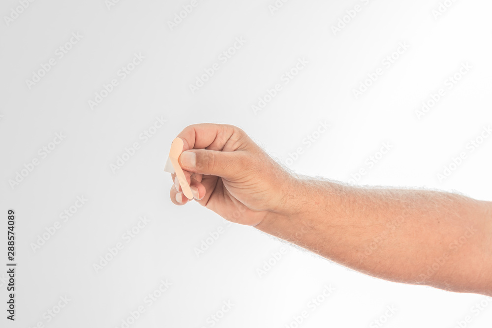 Man's hand holding a Band-Aid on a white background. Space to write.