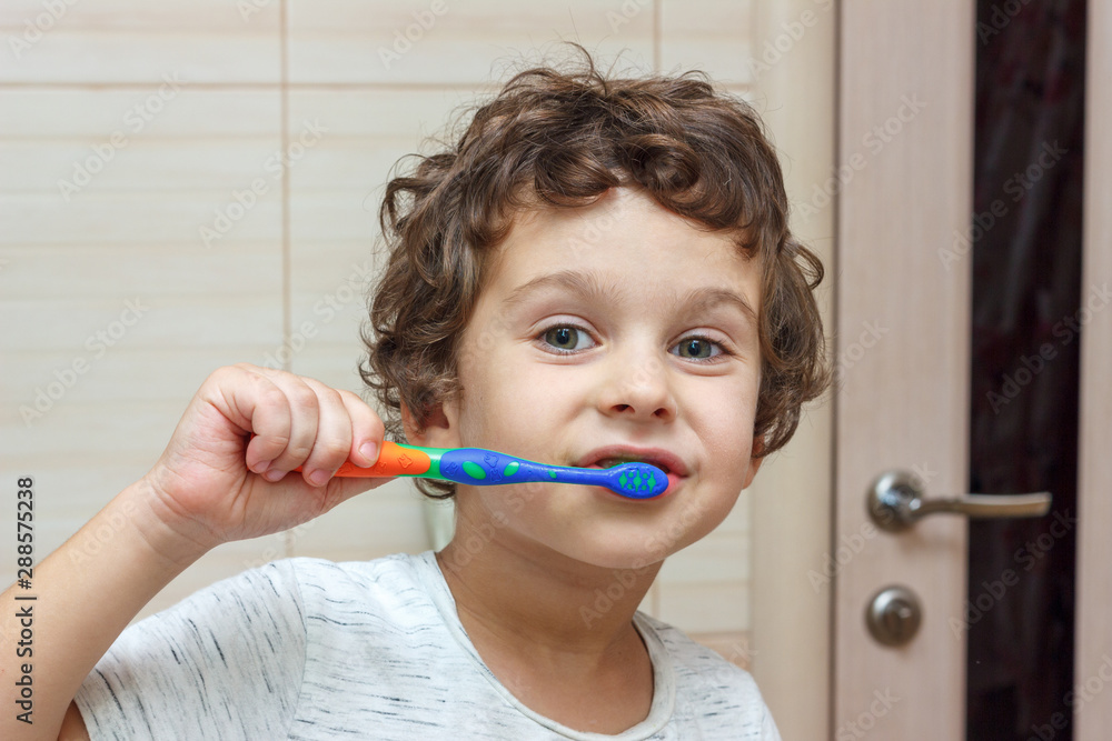 Happy little boy brushing his teeth in bathroom in front of mirror, oral hygiene Happy little boy brushing his teeth in bathroom in front of mirror, oral hygiene
