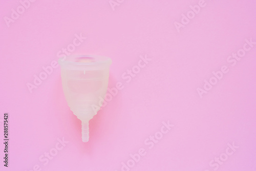 White Menstrual cup on pink background. Alternative feminine hygiene product during the period. Women health concept photo