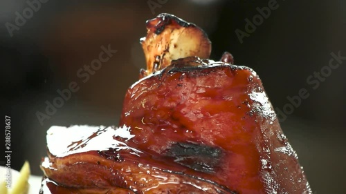 CLose up top of burining lamb shank. Shank of lamb with flavor sauce and spices, slow-motion, macro view. photo