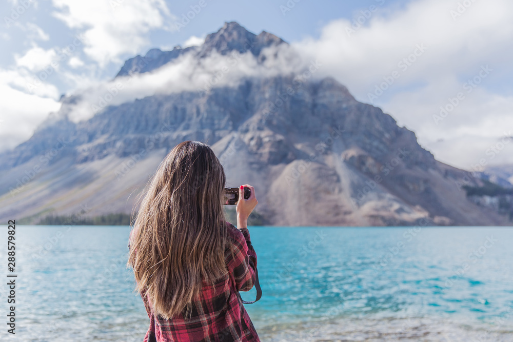 Woman taking photo at Bow Lake, Banff National Park, Alberta, Canada on a clear sunny day Woman taking photo at Bow Lake, Banff National Park, Alberta, Canada on a clear sunny day