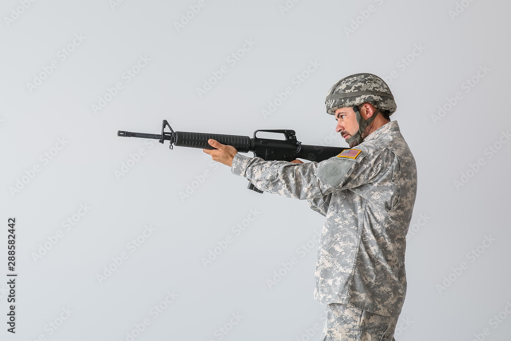 Soldier in camouflage taking aim on light background Soldier in camouflage taking aim on light background