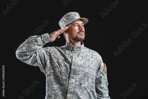 Saluting soldier on dark ba...