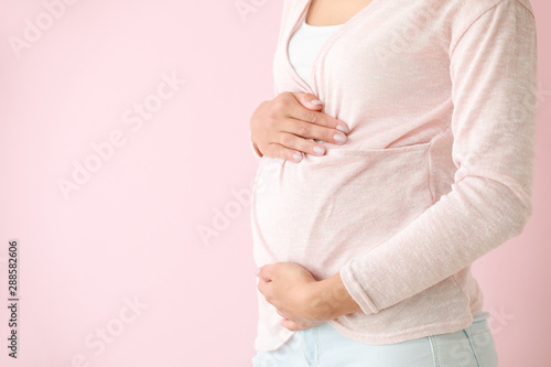 Young pregnant woman on color background