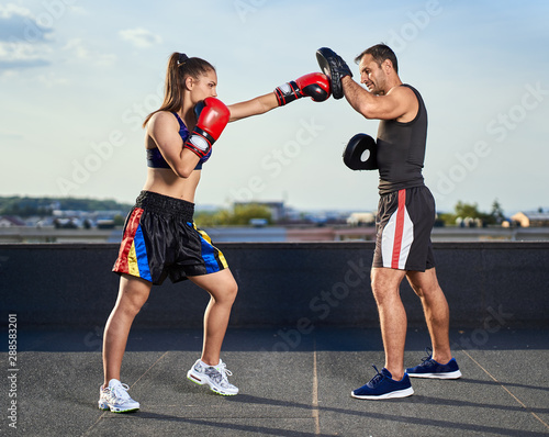 Young woman boxer hitting pads outdoor