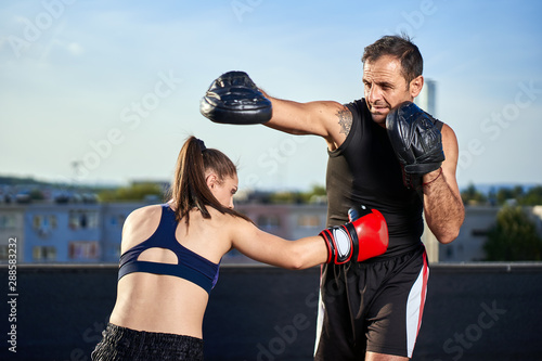 Young woman boxer hitting pads outdoor