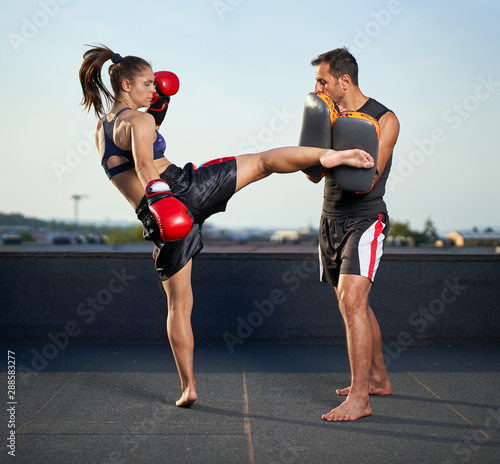 Canvas Print Young woman kickboxer in urban environment, training