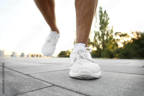 Handsome sporty man running outdoors, closeup
