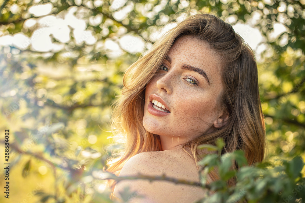 Happy girl with freckles posing in sunny garden. Happy girl with freckles posing in sunny garden.