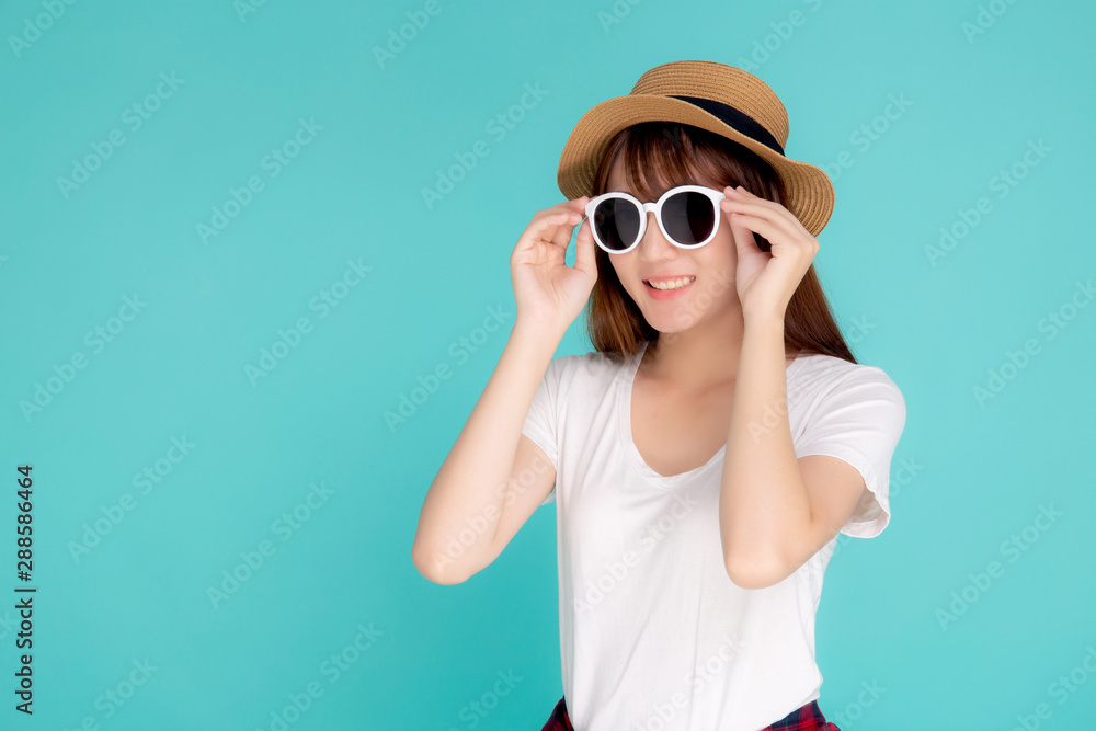 Beautiful portrait young asian woman wear hat and holding sunglasses smiling confident enjoy journey summer trip in vacation isolated on blue background, tourist asia girl cheerful with travel. Beautiful portrait young asian woman wear hat and holding sunglasses smiling confident enjoy journey summer trip in vacation isolated on blue background, tourist asia girl cheerful with travel.