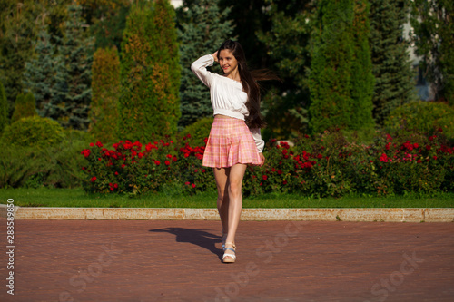 Pretty stylish brunette girl in plaid skirt and white blouse © Andrey_Arkusha