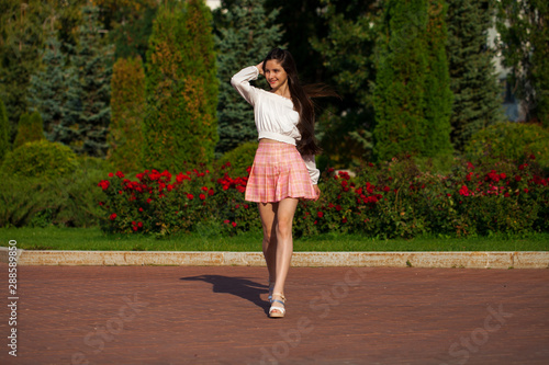 Pretty stylish brunette girl in plaid skirt and white blouse