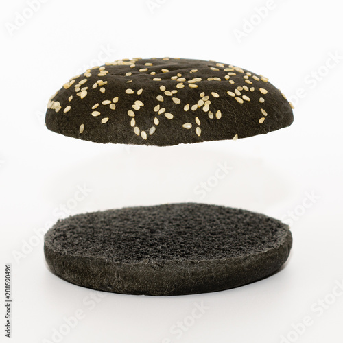 Two black halves of a burger bun flying over a white background
