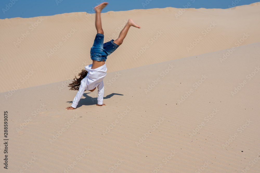 Young boy doing a cartwheel on sand