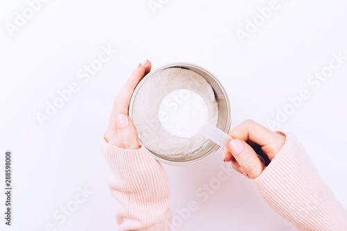 A jar with collagen powder and scoop spoon in woman hands. photo