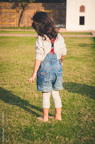 Little girl stepping on green grass barefoot