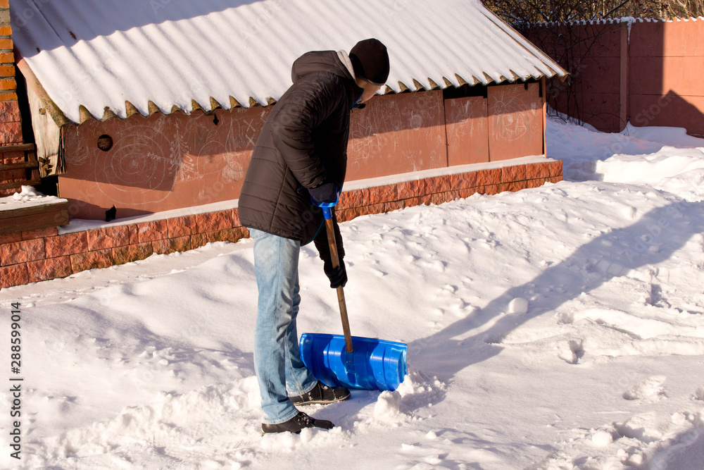 A teenager shoveling snow in his yard. The concept of a snowy winter.