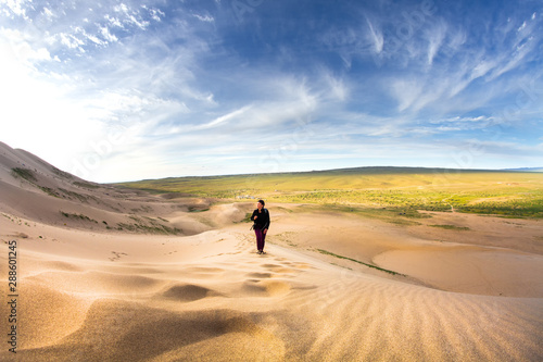 Woman walking in the mongolian desert sand dunes. Young woman walking golden sand on a bright summer day, Mongolia holliday vacation concept.