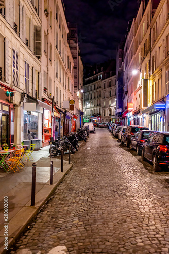 Street of night old Paris with glittering lights of shop windows