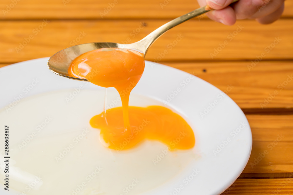 白いお皿に生卵の黄身がスプーンから割れて落ちる瞬間 料理 Stock 写真 Adobe Stock