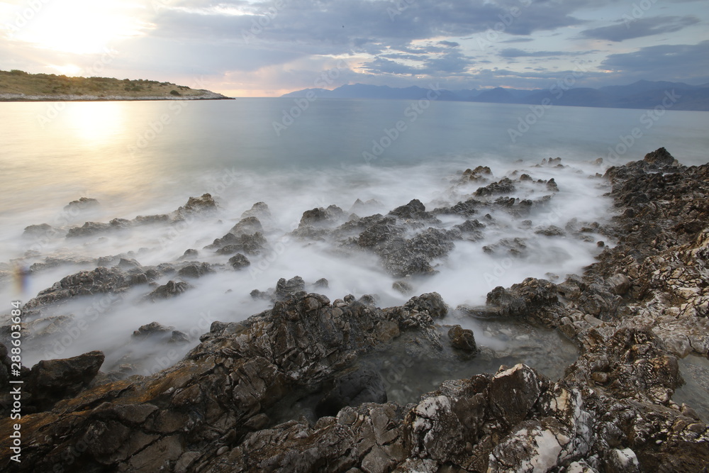 Sunset on a rocky Corfu beach with smooth waves