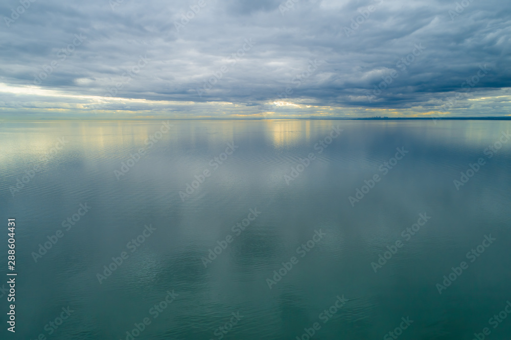Minimalist seascape of storm clouds over smooth sea at sunset