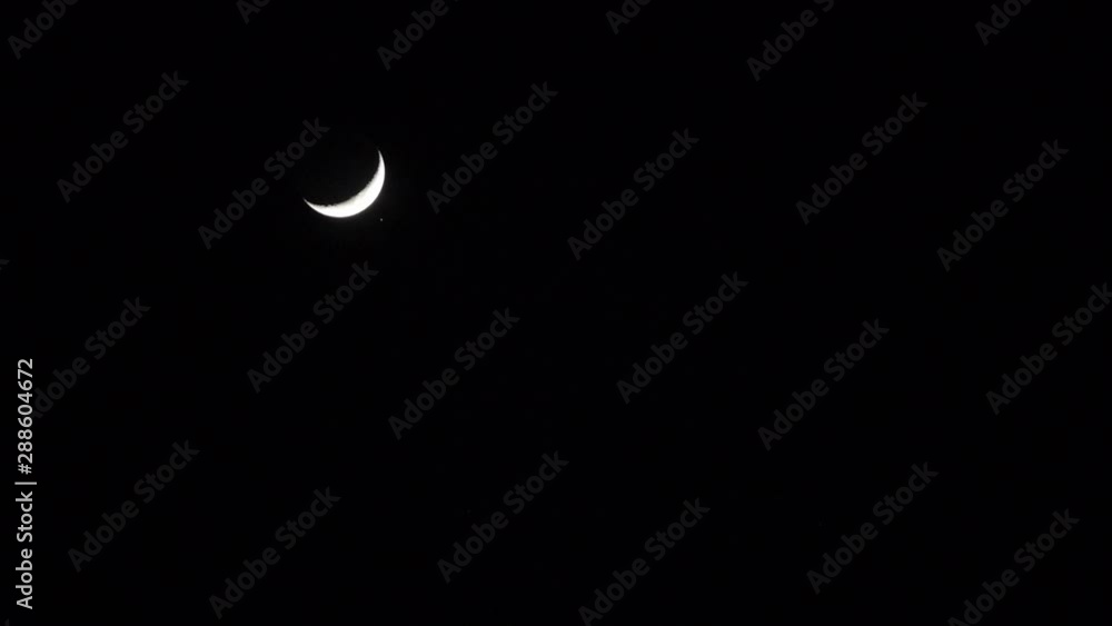 A time lapse shot of a crescent moon lowering in the frame. A time lapse shot of a crescent moon lowering in the frame.