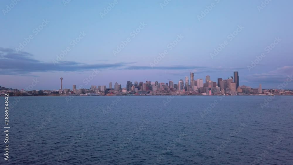 Distant view of Downtown Seattle during sunset traveling aboard Washington State Ferry. calm water in foreground Distant view of Downtown Seattle during sunset traveling aboard Washington State Ferry. calm water in foreground
