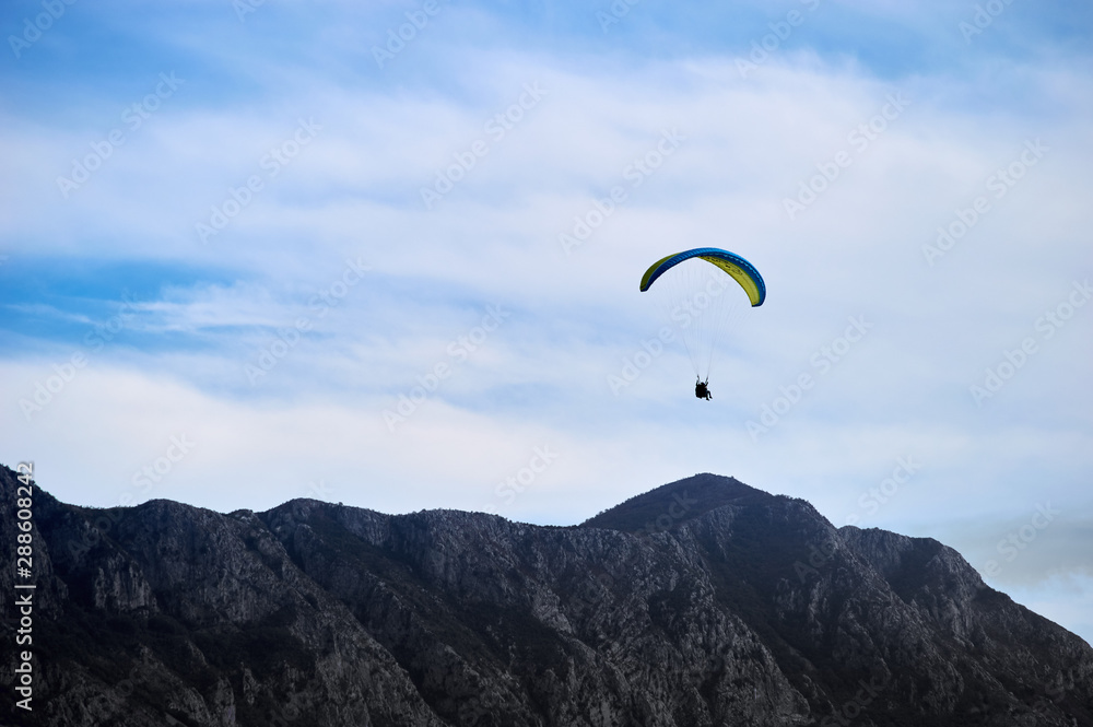 parachutist gliding in the blue sky above the mountain parachutist gliding in the blue sky above the mountain