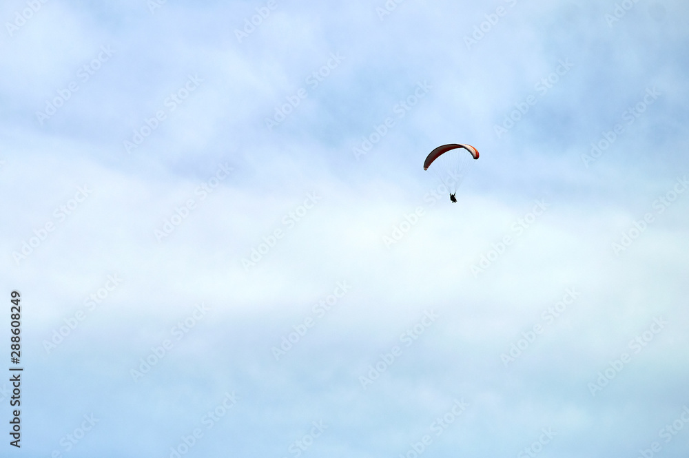 skydiver gliding in the clouds on yellow and blue wing skydiver gliding in the clouds on yellow and blue wing