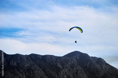 parachutist gliding in the blue sky above the mountain