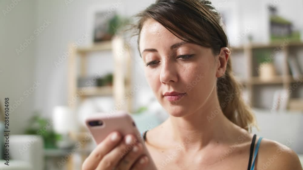 Woman uses the phone while relaxing after doing yoga