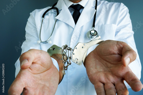 Medical malpractice concept. Doctor with handcuffs on hands. photo