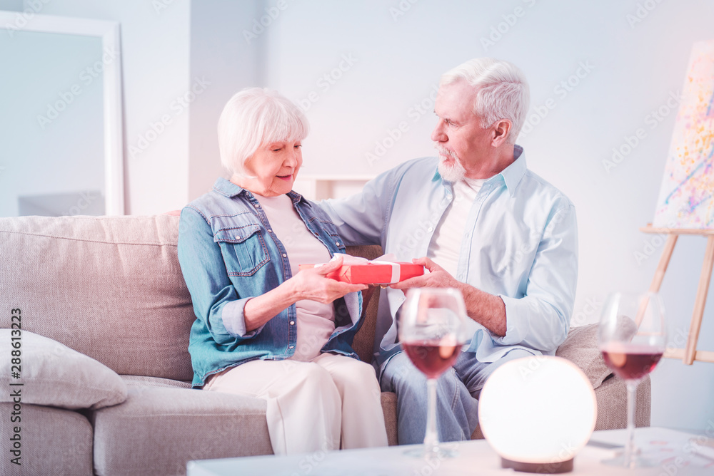 Retired woman feeling surprised receiving present from husband Retired woman feeling surprised receiving present from husband