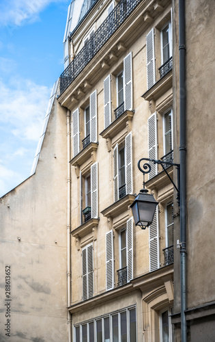 The facade of an old building with lantern and shutters on the windows