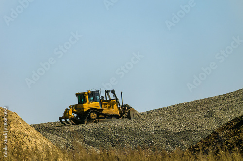 Motorized bulldozer raking rubble piles to uphill. Road building industry.