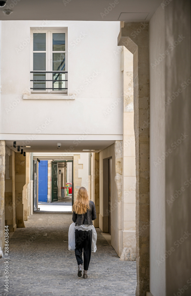 The girl with the package goes through the courtyards in Paris